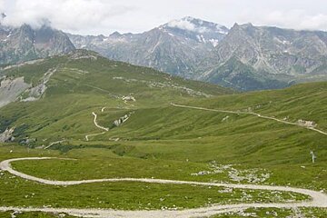 A dirt road in the mountains with mountains in the background