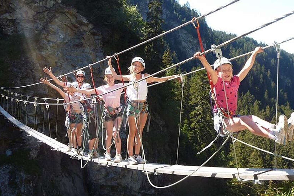 An image of a group of children on a via ferrata climbing course in the Alps, summer activity with Meribel Bureau des Guides