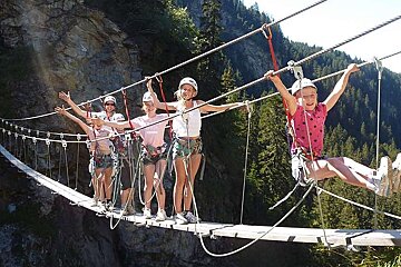 An image of a group of children on a via ferrata climbing course in the Alps, summer activity with Meribel Bureau des Guides