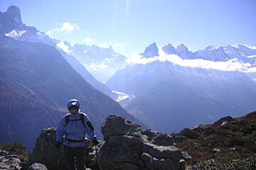 A person standing on top of a mountain with mountains in the background