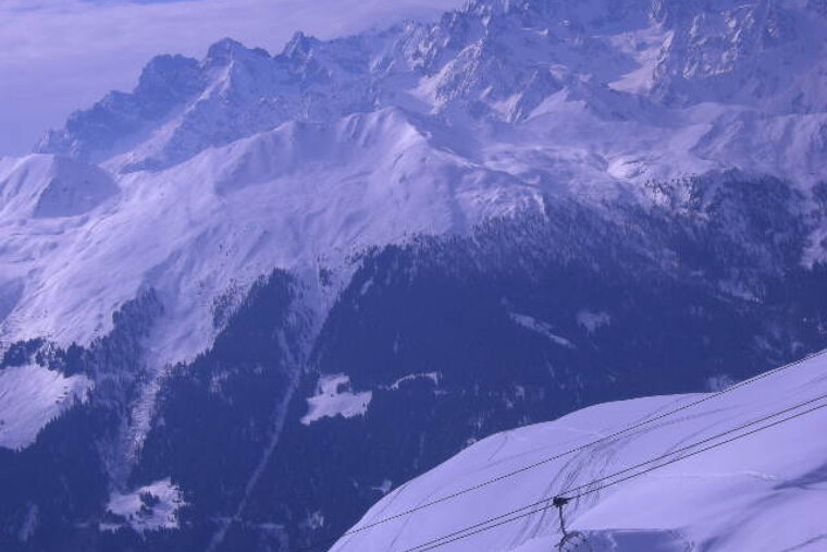 A ski lift is going up a snowy mountain
