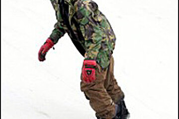 A man in a camouflage jacket is riding a snowboard