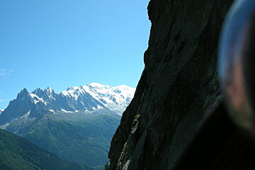 A mountain range with a blue sky and a cliff in the foreground