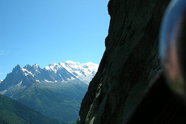 A mountain range with a blue sky and a cliff in the foreground