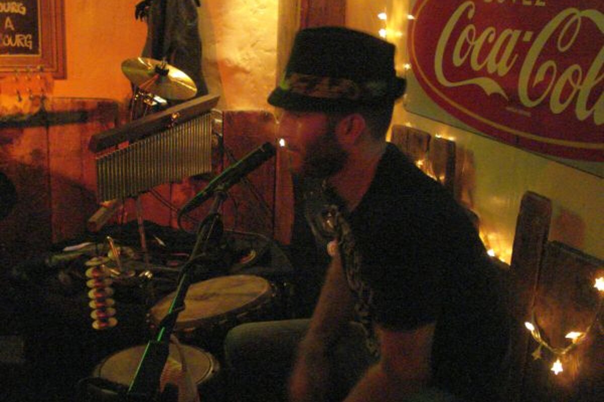 A man playing drums in front of a coca cola sign