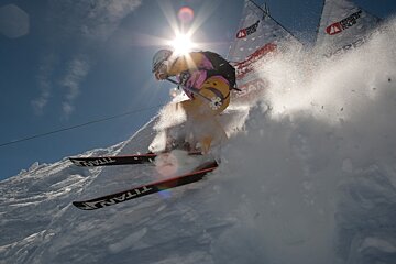 A person is skiing down a snow covered slope and their skis say titan