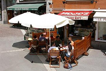 A group of people sit outside mojo 's sandwich cafe