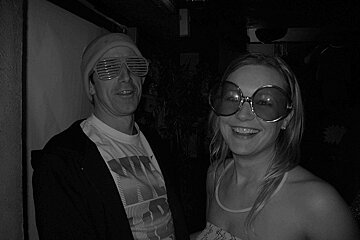 A man wearing sunglasses stands next to a woman wearing sunglasses