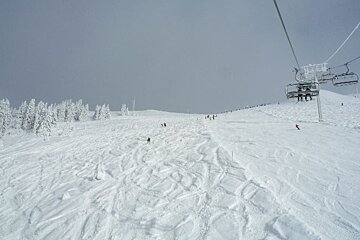 A ski lift going up a snow covered mountain
