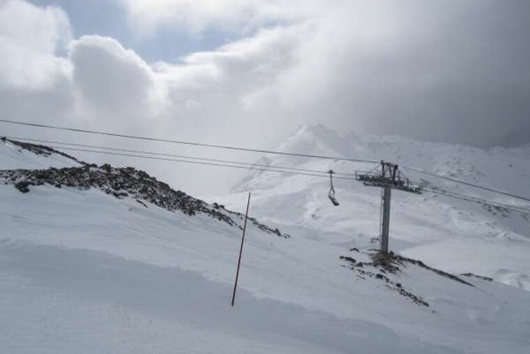 A ski lift is going up a snow covered mountain