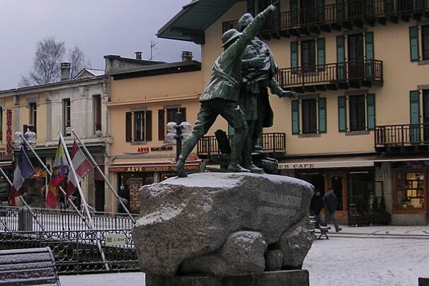 A statue in front of a building that has the word cafe on it