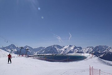 A person skiing down a snowy slope with mountains in the background