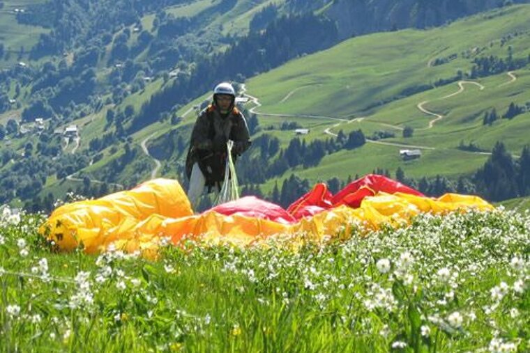 A man is standing in a field with a parachute