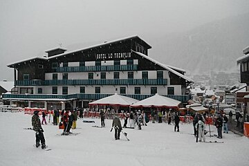 An image of a large building in the snow with parasols and tables at the front