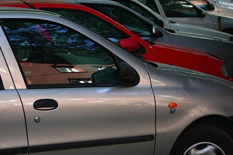 A silver car is parked next to a red car
