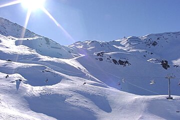 The sun is shining brightly on the snowy mountains