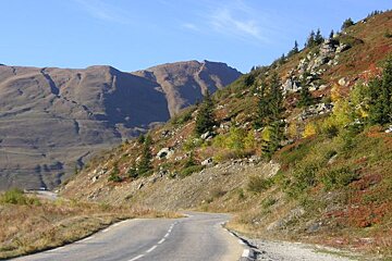 A road with mountains in the background and trees on the side