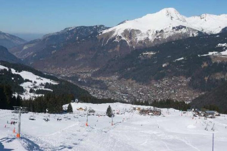 A ski resort with a mountain in the background and a ski lift in the foreground