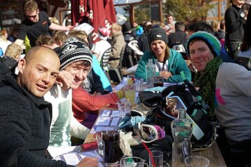 An image of a group of skiers enjoying some mountain food in the sunshine