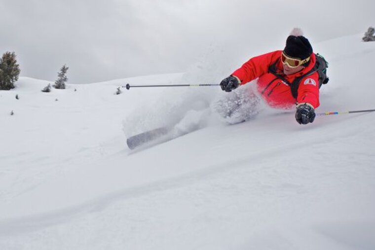 A person skiing down a snow covered slope wearing a red jacket