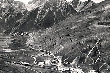 A black and white photo of a valley with mountains in the background