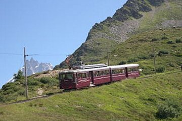 A train going up a hill with a mountain in the background