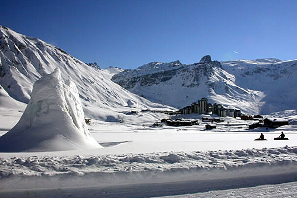 A snowy landscape with a ski resort in the background