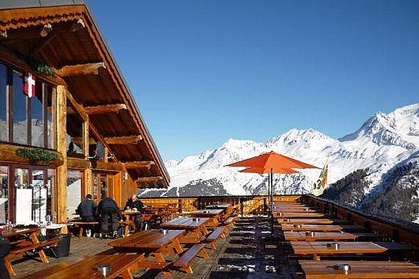 An image of a ski resort restaurant terrace with snowy mountains in Montchavin Les Coches, La Plagne Paradiski