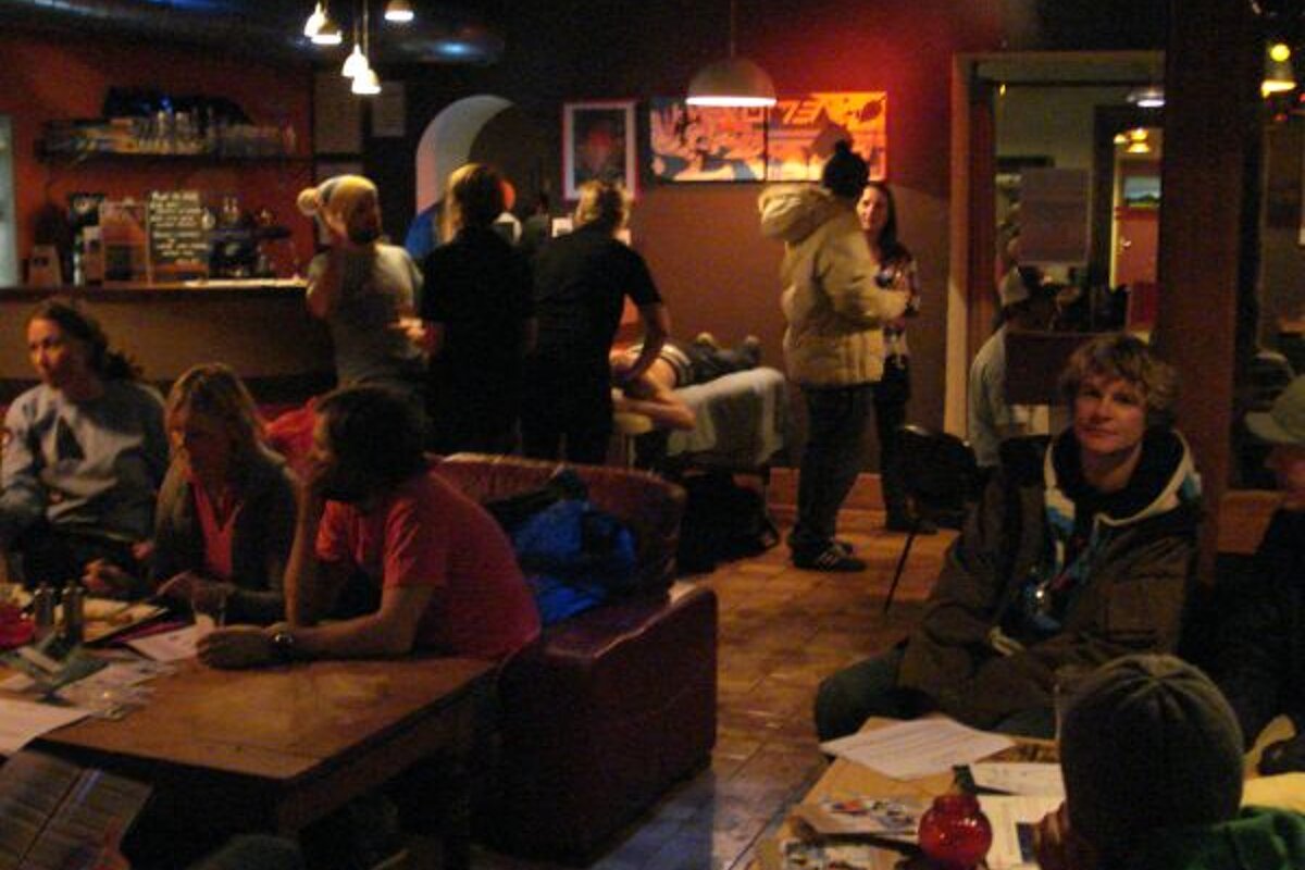A group of people are gathered in a room with a sign on the wall that says ' a ' on it