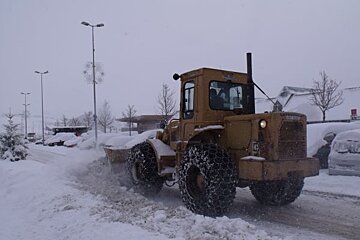 A caterpillar tractor is clearing snow from a parking lot
