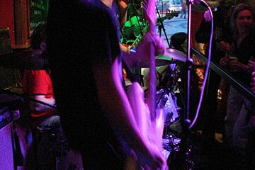 A man playing a guitar in front of a microphone in a dark room