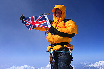 A man in a yellow jacket holds up a british flag