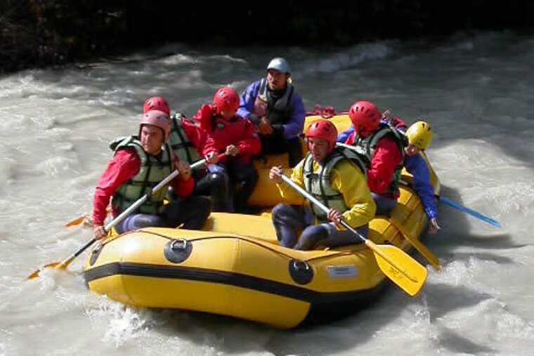 A group of people are rafting down a river in a yellow raft