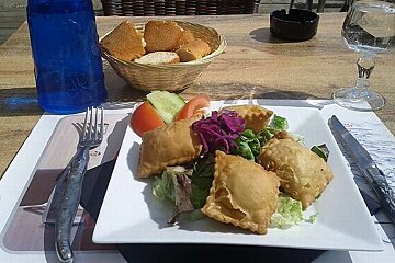 an image of a plate of pastry parcels filled with cheese with a side salad