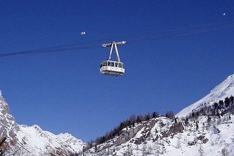 A ski lift is flying over a snowy mountain