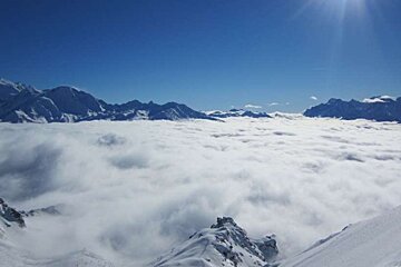 Mountains covered in snow and clouds with a blue sky