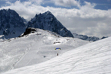 A person flying a parachute over a snowy mountain