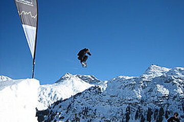 A snowboarder is jumping in the air in front of a banner that says head