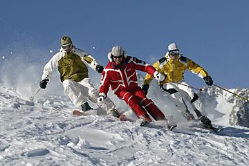 Three people are skiing down a snow covered slope