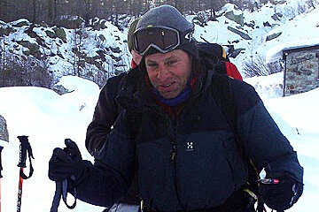 A man wearing a black jacket with the letter h on it