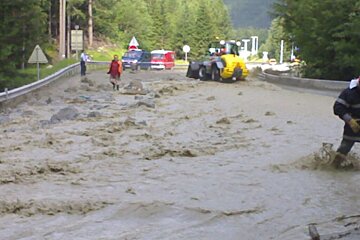 A flooded road with a yellow tractor in the background