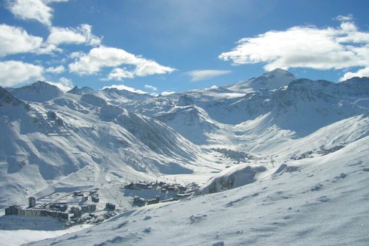 A snowy mountain range with a ski resort in the distance