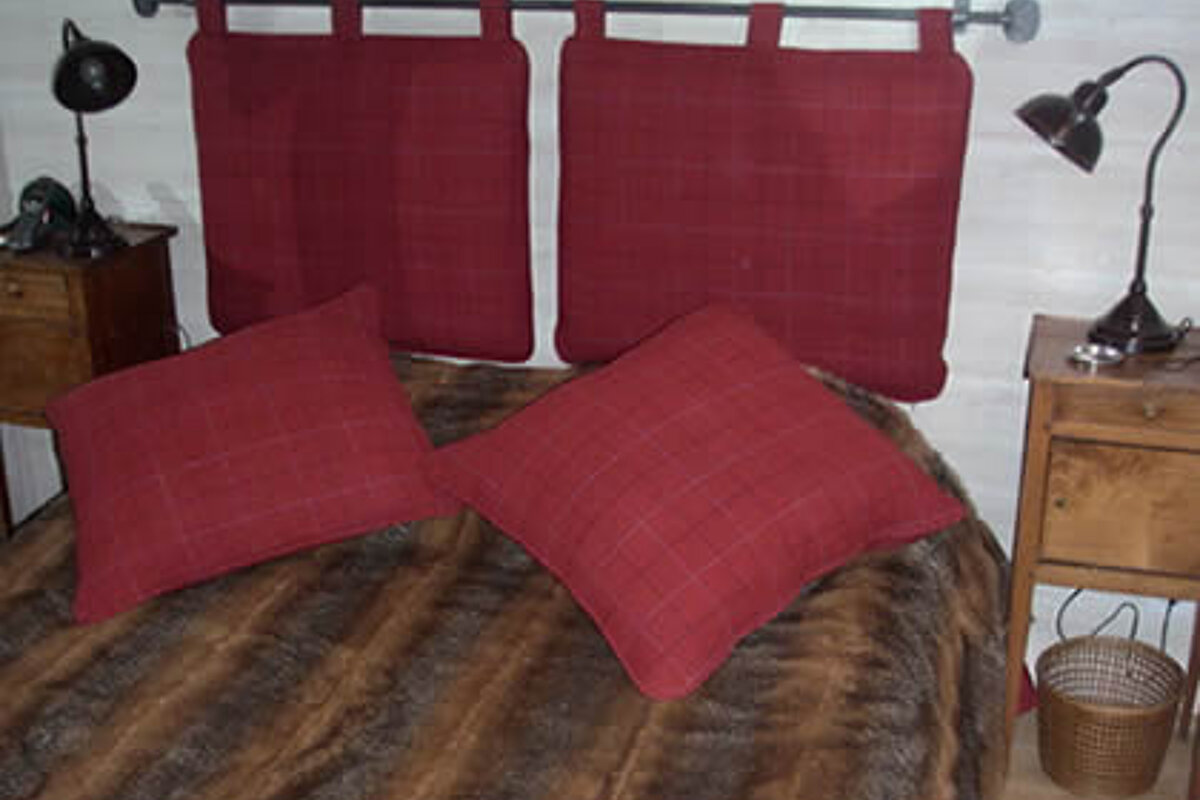 A bed with red pillows and a fur blanket