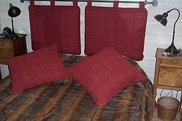 A bed with red pillows and a fur blanket