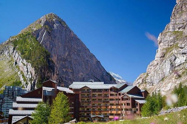 A large building in the middle of a valley with a mountain in the background