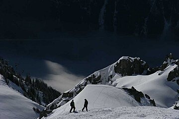 Two people standing on top of a snow covered mountain