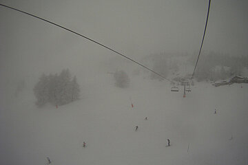 A ski lift is going down a snowy mountain