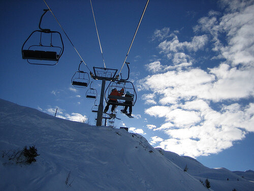 Skiers on a ski lift with a blue sky in the background