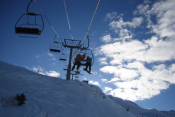 Skiers on a ski lift with a blue sky in the background