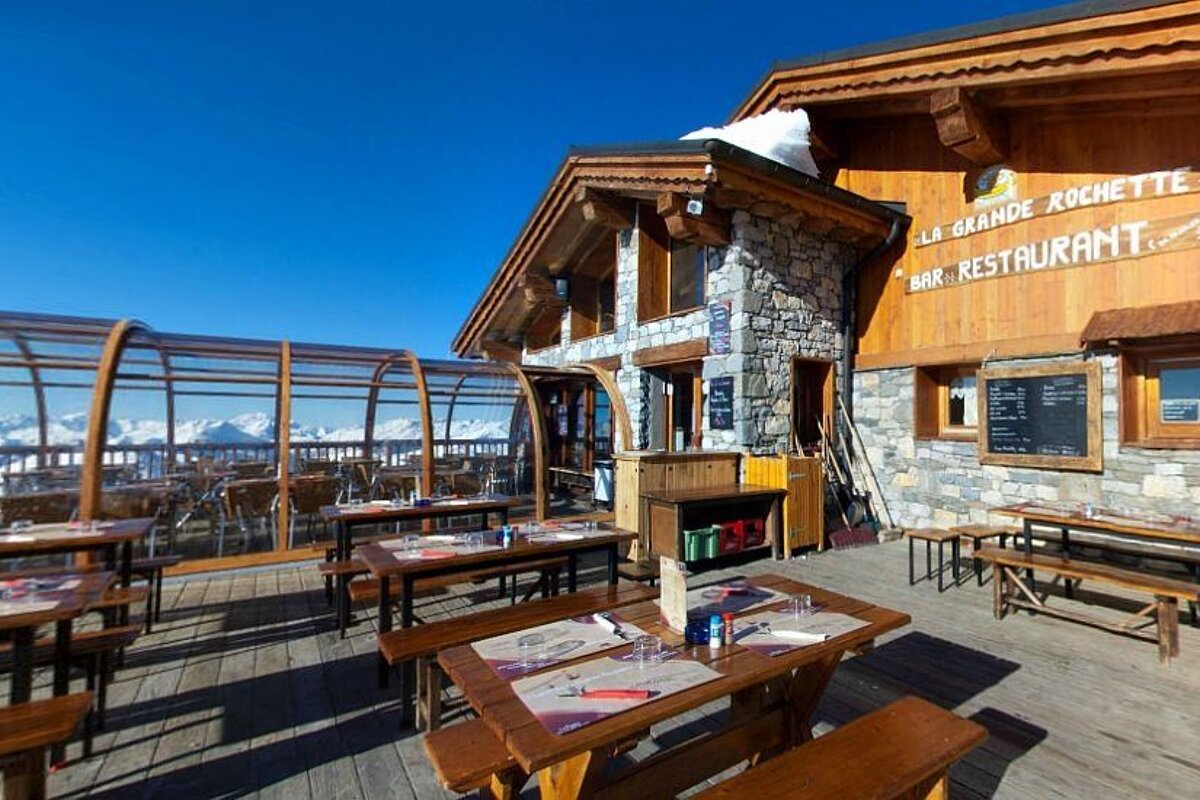 An image of a ski resort restaurant and terrace with mountains in the background in La Plagne Paradiski